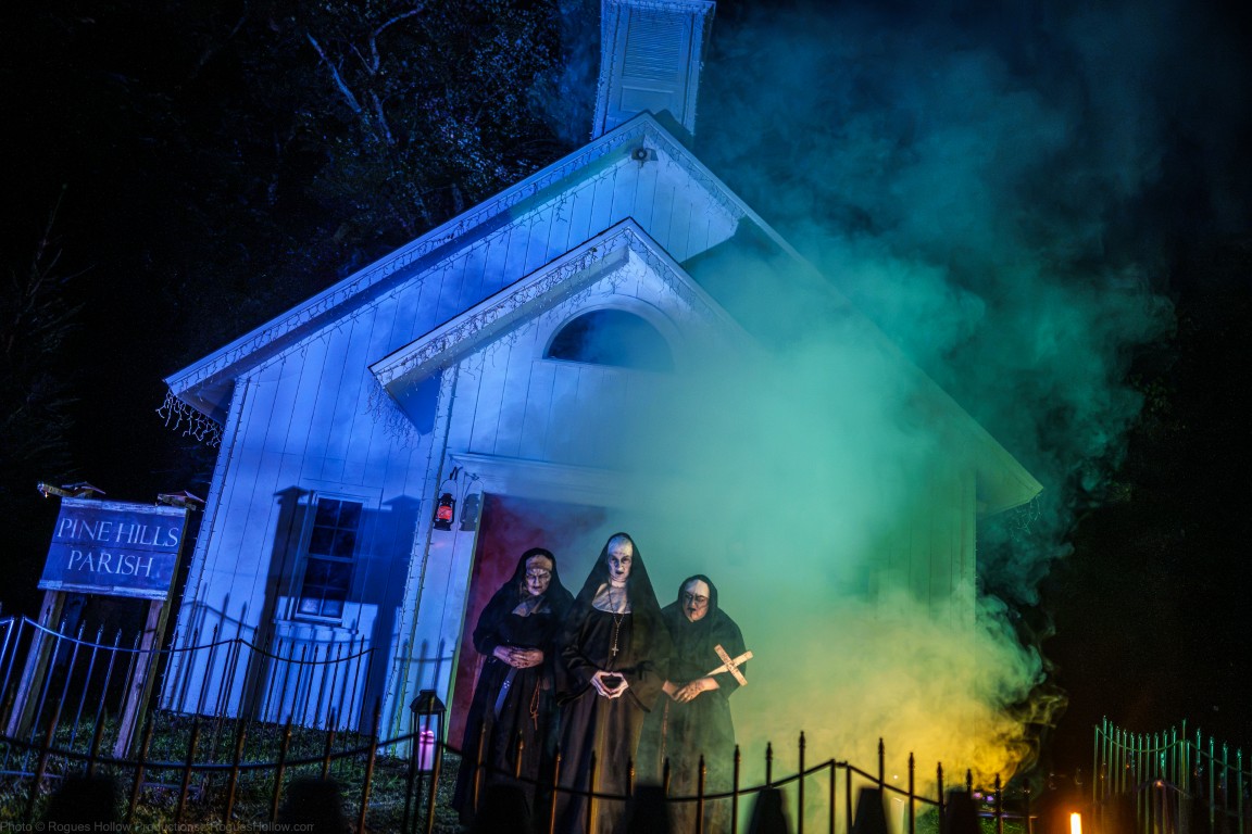 Three costumed nuns stand in colored fog outside the Pine Hills Parish chapel at Legends of Fear in Shelton